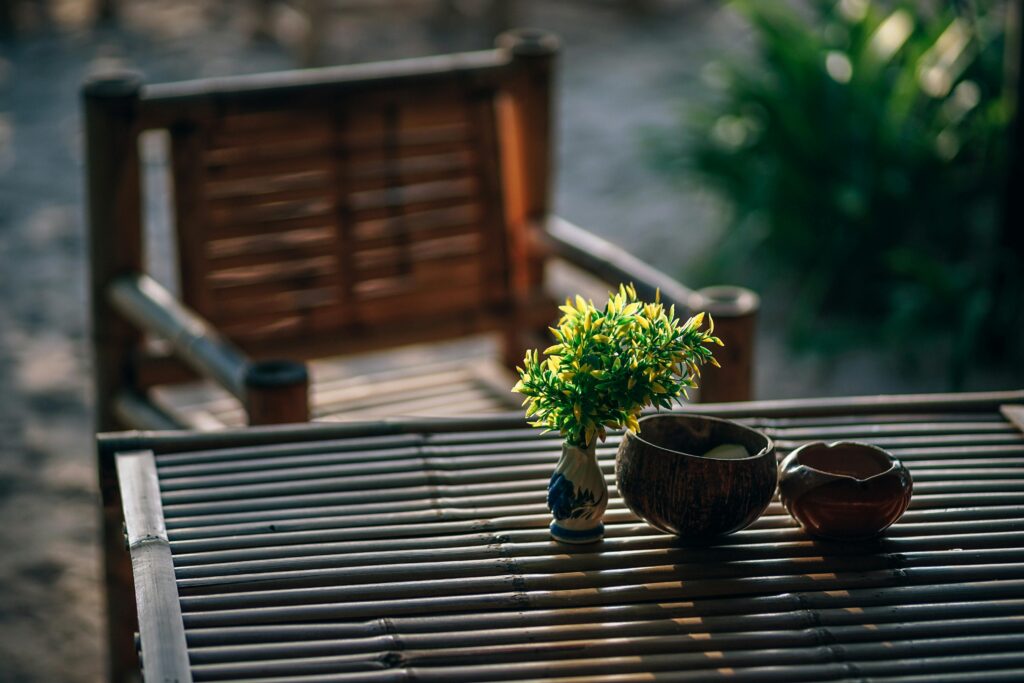Serene bamboo seating arrangement with vase and greenery in a Thai garden setting.