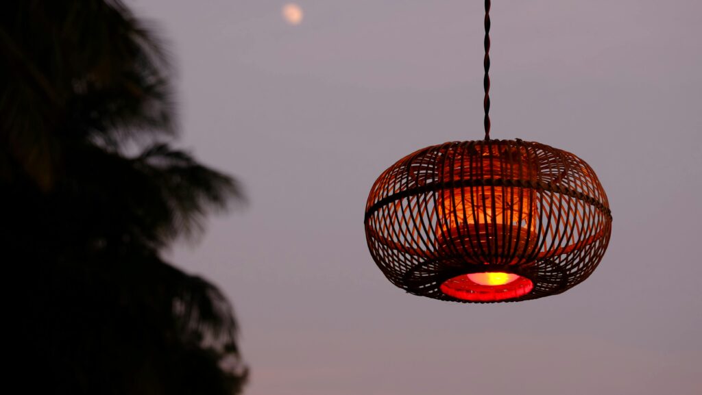A woven lantern glows warmly at twilight, set against a serene evening sky.