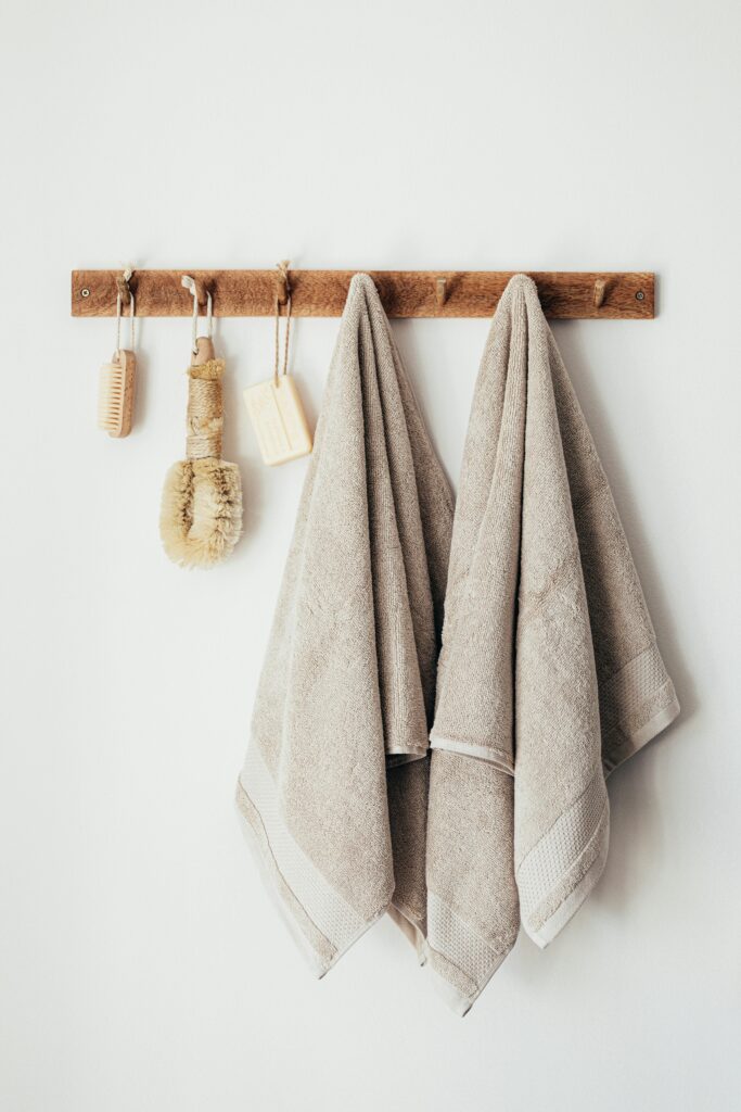 Minimalist bathroom setup featuring eco-friendly towels and natural accessories hanging on a wooden rack.