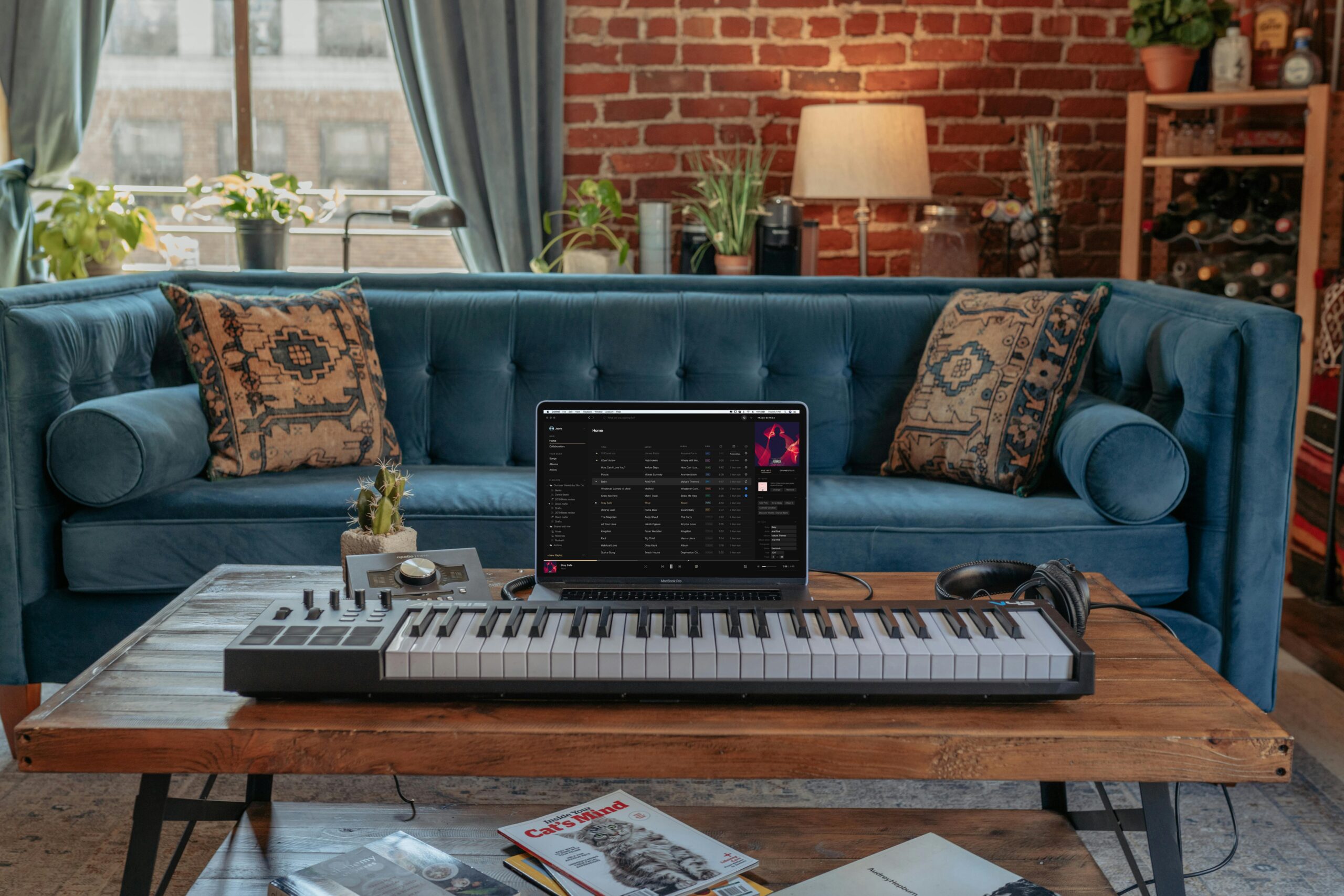 A stylish home recording studio setup featuring a keyboard, laptop, and cozy living room decor.